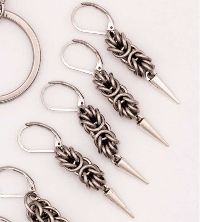 Silver earrings with intricate designs on a light pink background